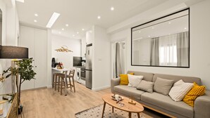 A modern living room with a sofa, coffee table, and dining area. - Lazuli Hermes Apartments (Larnaca)