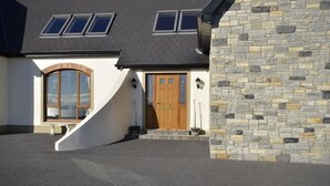 A two-story house with a stone facade, a wooden front door, and a large arched window.
