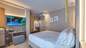 A modern hotel room with a large bed, a desk with a flat-screen TV, a wardrobe, and an air conditioning unit. - VILLA SALISA' (Menfi)