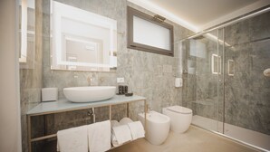 A modern bathroom with a large mirror, a glass shower enclosure, and a marble-tiled wall. - VILLA SALISA' (Menfi)