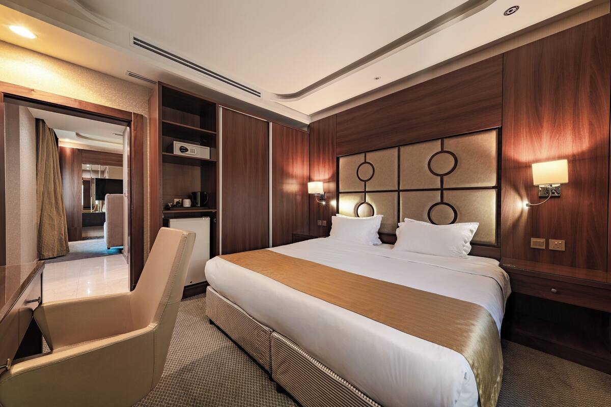 A hotel room with a large bed, a seating area, and a built-in desk.