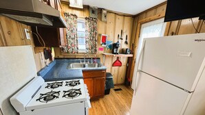 Une cuisine de taille réduite équipée d’une cuisinière à gaz, d’un évier et d’un réfrigérateur blanc.