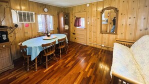 Une pièce aux murs en bois, avec une table à manger et des chaises, un canapé et un miroir.