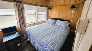 Une chambre à coucher avec un lit, une chaise, une fenêtre et une lampe.