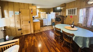 Une cuisine de taille réduite, avec des meubles de rangement en bois, une table à manger et un téléviseur.