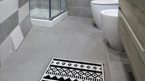 Un baño moderno con cabina de ducha de vidrio, inodoro y lavamanos con barra para toallas.