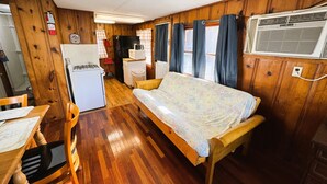 A compact RV interior with a kitchenette, a bed, and a dining area.