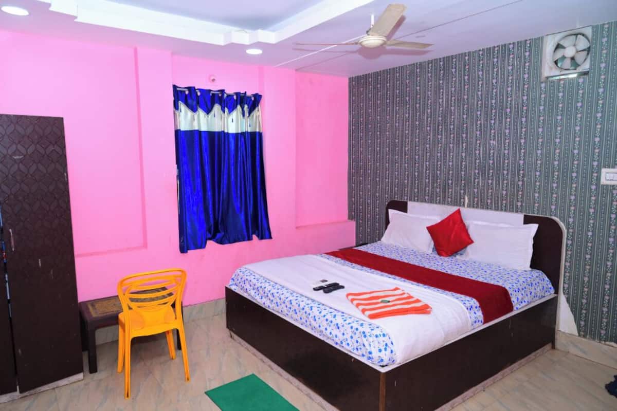 A bedroom with a bed, a chair, a ceiling fan, and a window with curtains.
