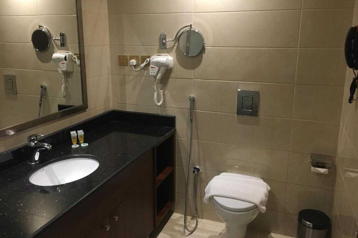 Een badkamer met een wastafel, spiegel, handdoek en douche.