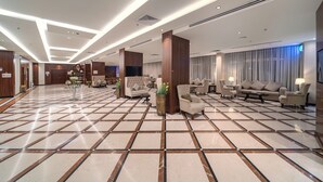 A spacious lobby with a tiled floor, multiple seating areas, and a television. - Sunday Harbour Gateway Jeddah Beach Formerly Vivid Plaza Hotel (Jeddah)