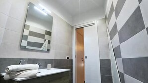 A bathroom with a mirror, sink, towel, and a door leading to another room. - Napoli Vesuvio By Dimorra (NAPOLI)