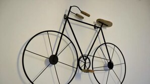 A wall-mounted bicycle sculpture with a wooden seat and handlebars. - Napoli Vesuvio By Dimorra (NAPOLI)