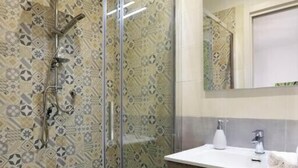 Une salle de bain avec une douche à parois de verre, des carreaux décoratifs, un meuble-lavabo en bois et un miroir.
