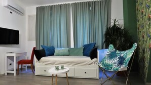 Un salon moderne avec un canapé, une petite table, un fauteuil rouge et un téléviseur fixé au mur.