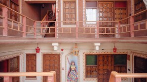 A multi-level building with traditional architecture, including wooden doors and balconies. - NIrali Dhani Ethnic Resort (Jodhpur)