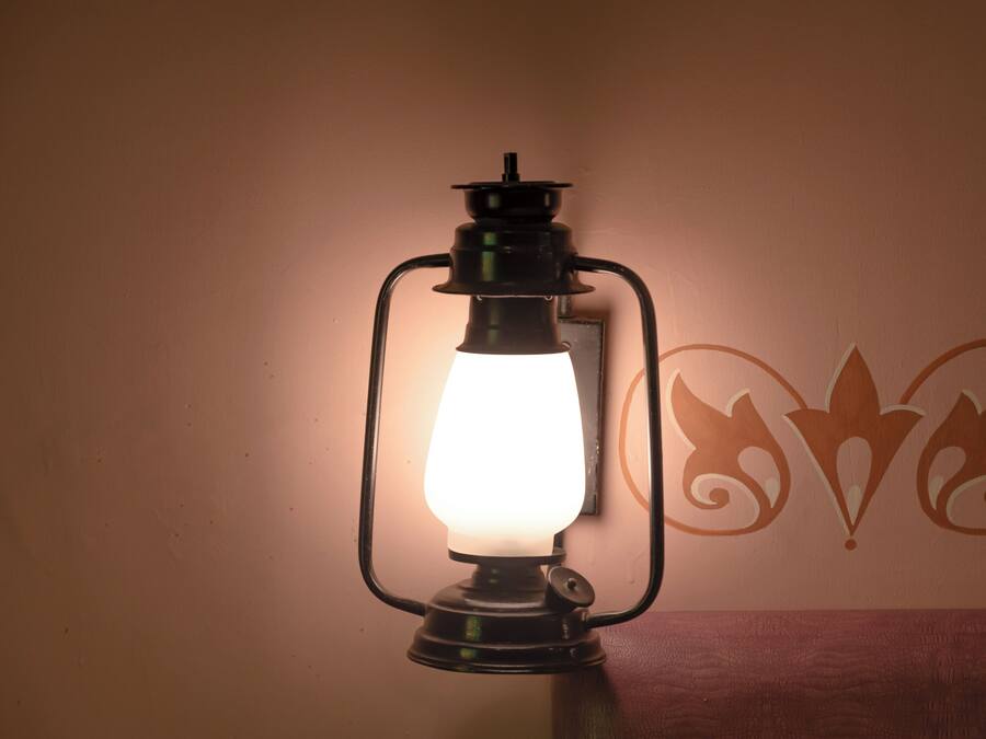 Una lámpara de pared con bombilla, un diseño decorativo en la pared y una superficie de madera debajo.