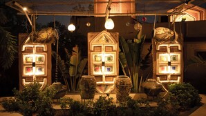 A garden with illuminated house-shaped structures, a hanging light fixture, and various plants. - NIrali Dhani Ethnic Resort (Jodhpur)