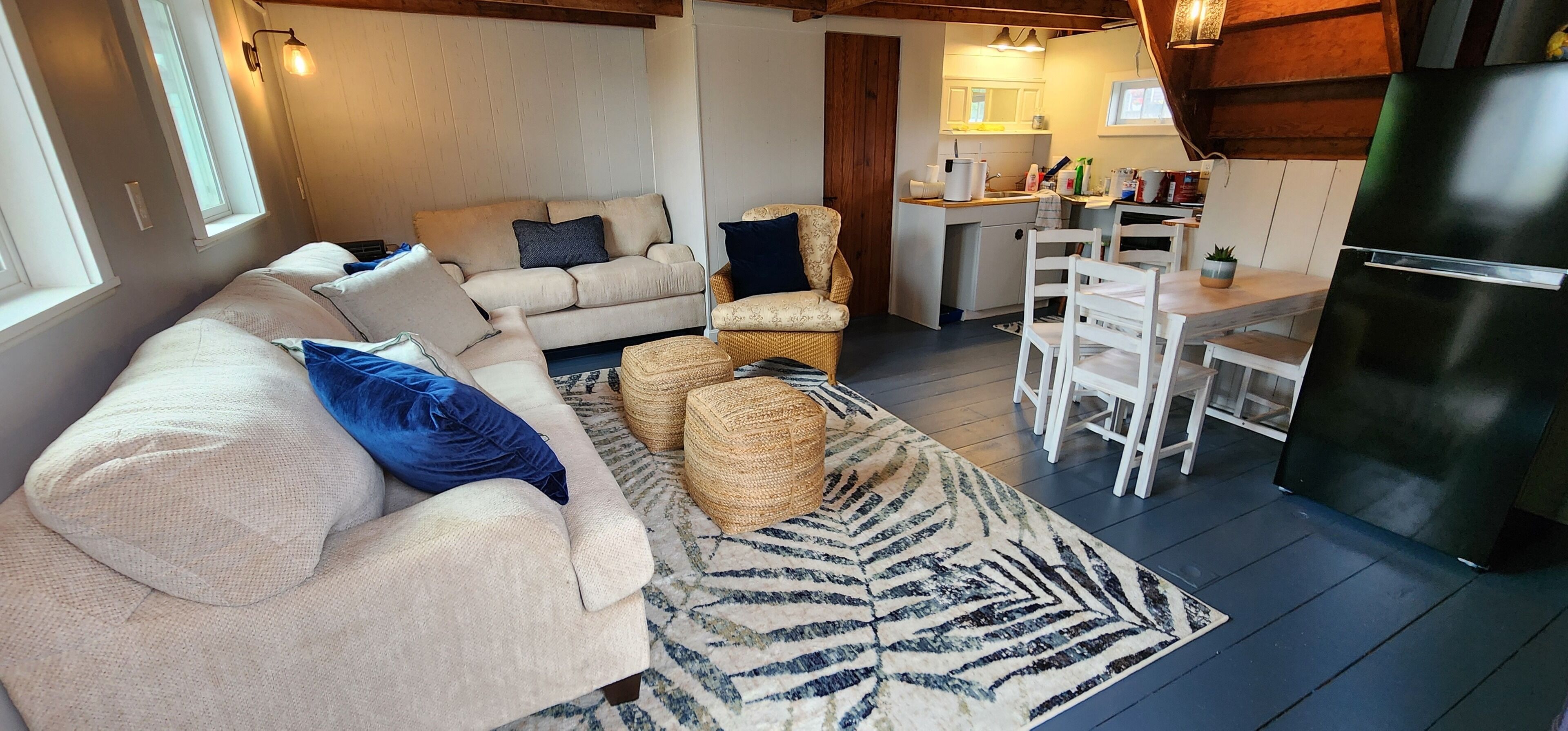 A cozy living room with a sofa, two armchairs, a coffee table, and a patterned rug.