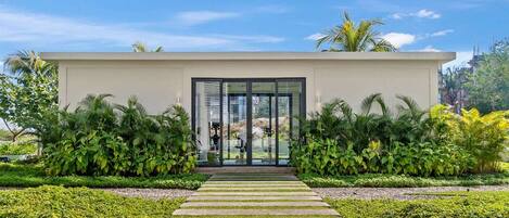 A modern building with a glass entrance, surrounded by lush greenery.