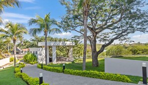 Un espacio exterior moderno con un sendero, una zona de estar y una estructura de pérgola.
