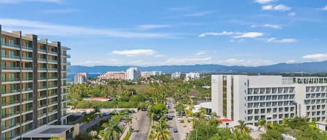 Un hotel moderno con varios pisos, un patio central y vistas a edificios y montañas distantes.