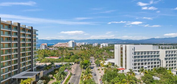Un hotel moderno con varios pisos, un patio central y vistas a edificios y montañas distantes.