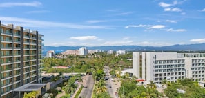 Un hotel moderno con varios pisos, un patio central y vistas a edificios y montañas distantes.