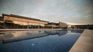 A modern building with a large glass facade and a swimming pool in front.