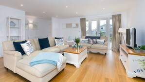 A modern living room with a beige sofa, a wooden coffee table, and a white cabinet.