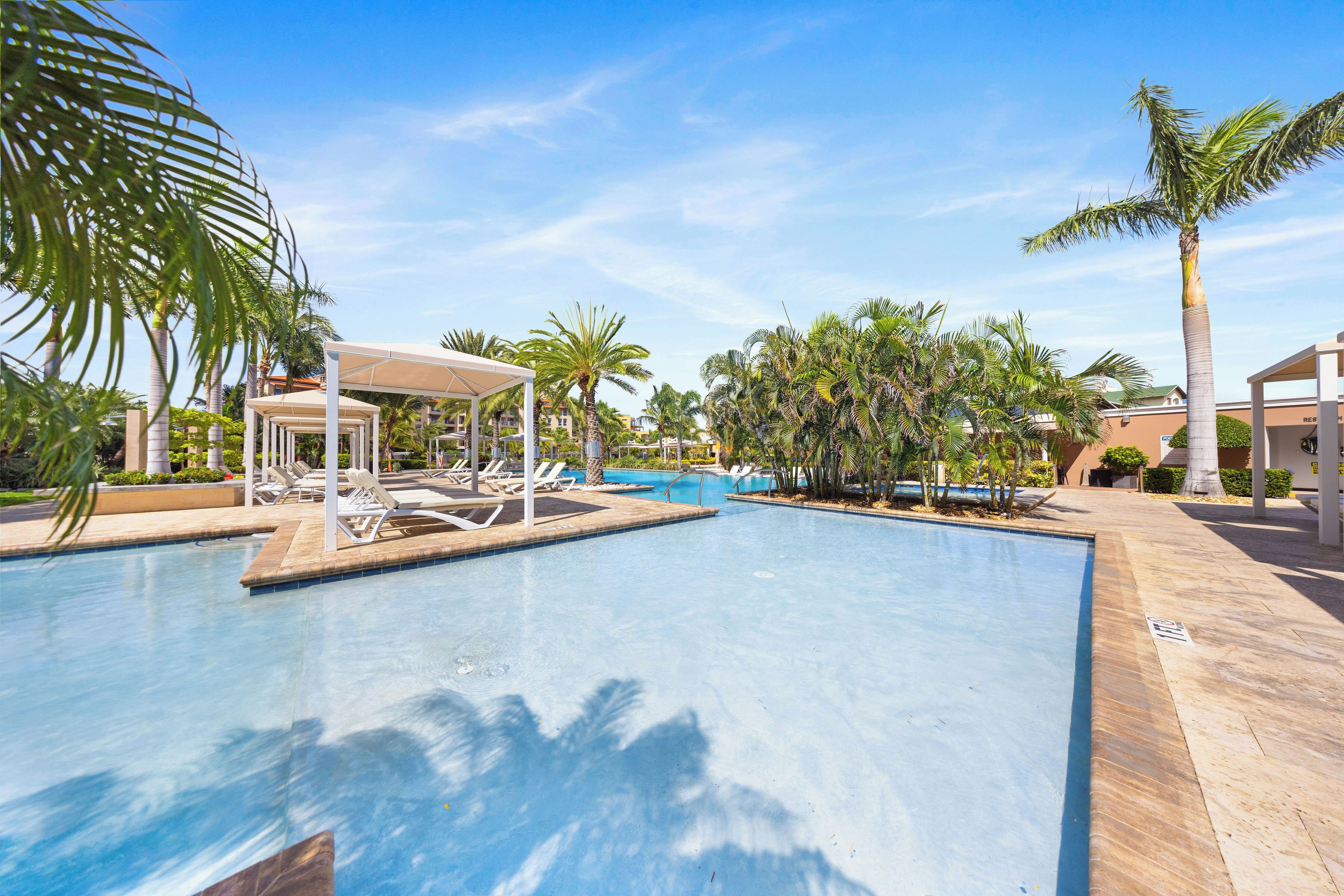 A swimming pool with lounge chairs and palm trees.