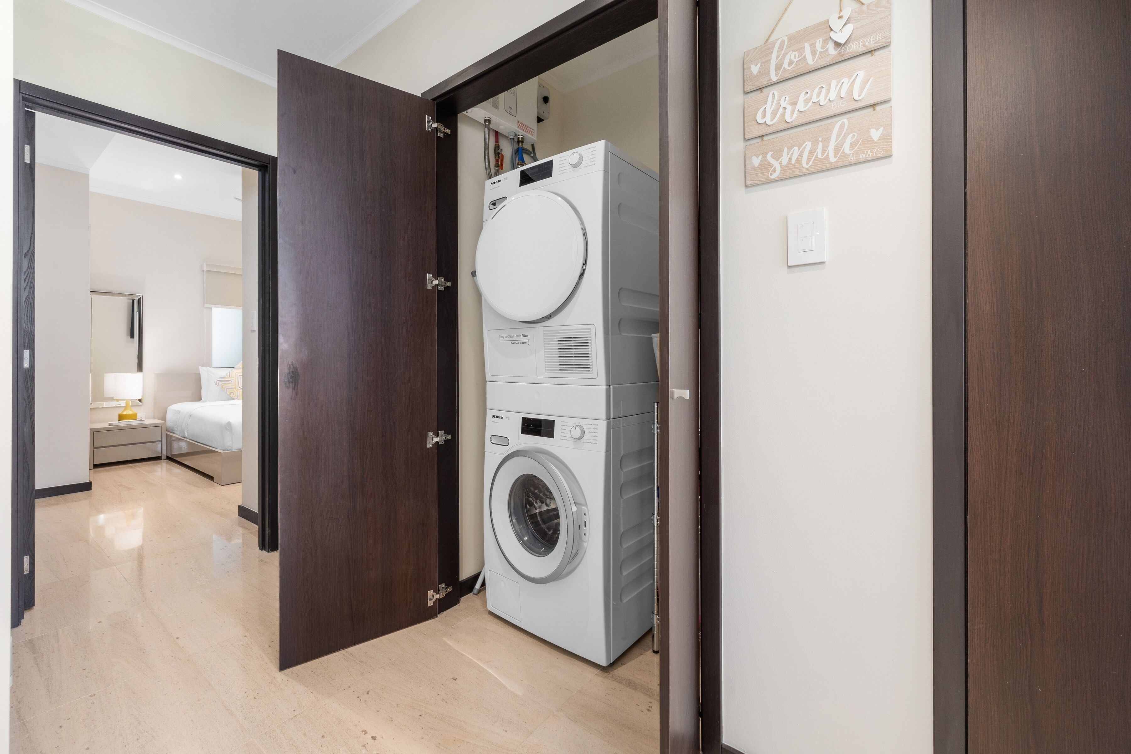 Une buanderie équipée d’un lave-linge à chargement frontal, d’une porte en bois et d’un mur décoré de motifs inspirants.