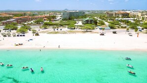 A coastal resort with a beachfront, clear turquoise waters, and several boats. - Bocobay LeVent Condos (Oranjestad)