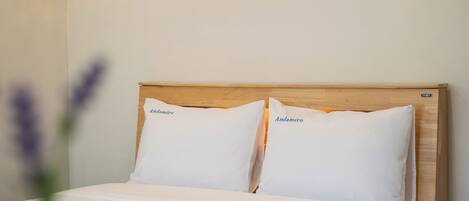 Un lit avec deux oreillers portant l’inscription « Andamiro » et une tête de lit en bois.