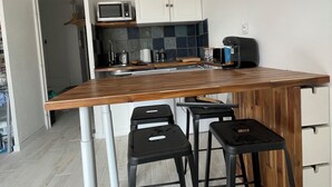 Eine moderne Küche mit einer Holzinsel, Barhocker, weißen Schränken und einer Mikrowelle.