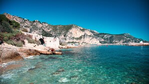A coastal scene with clear water, rocky shore, and a mountainous backdrop. - Delightful Studio With Private Parking, Beaulieu (Beaulieu-sur-Mer)