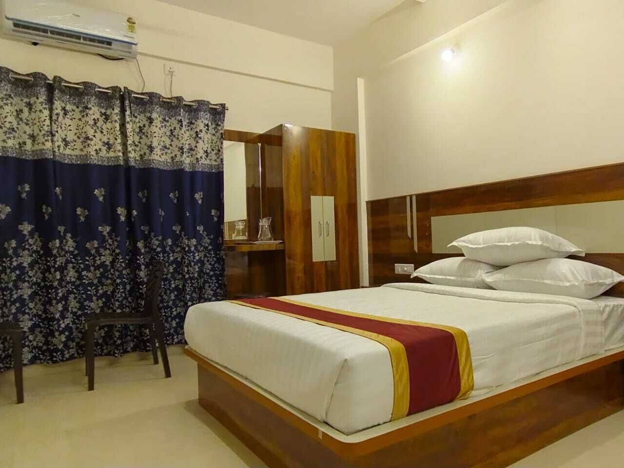 A hotel room with a bed, a wardrobe, a desk, and a chair.