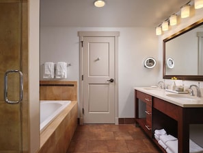 Un baño con bañera, lavamanos, tocador con cajones, espejo y puerta.