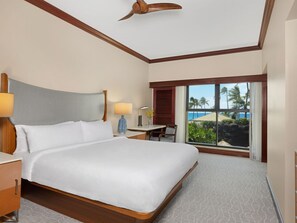 A spacious hotel room with a large bed, a desk, and a view of the ocean.
