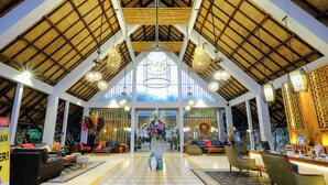A spacious lobby with a high ceiling, large windows, and a central floral arrangement. - Rumah Kito Resort Hotel Jambi by WH (Jambi)
