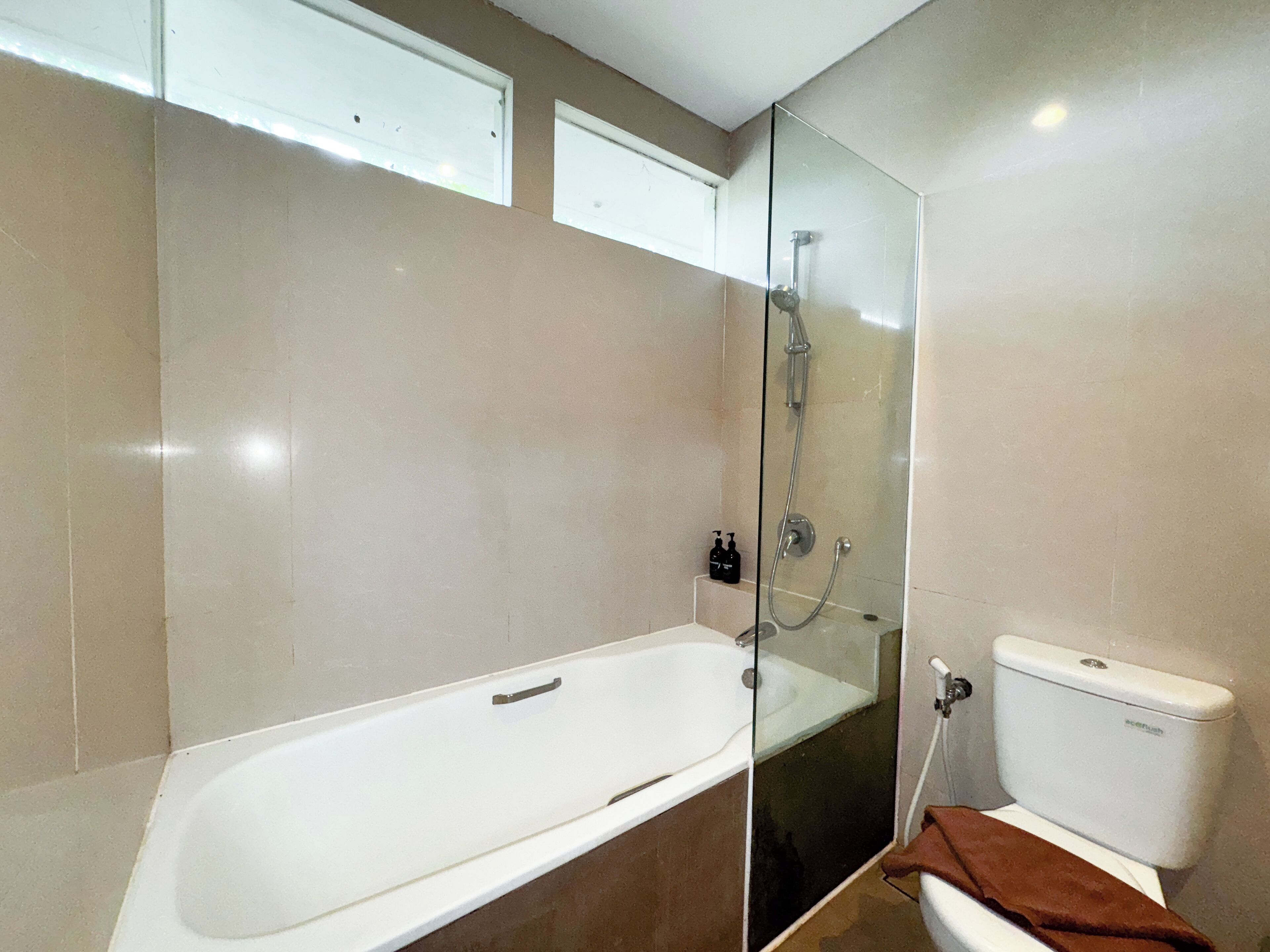 Un baño moderno con ducha de vidrio, una bañera blanca y un inodoro.