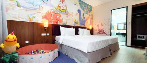 Una camera d'albergo con un letto grande, un affresco, un piccolo spazio giochi e un bagno visibile attraverso una porta aperta.