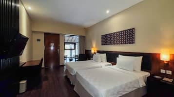Una habitación de hotel con dos camas, un escritorio y una televisión.