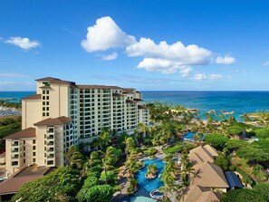A resort with a large building, a swimming pool, and palm trees.