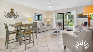 A spacious living area with a dining table, two sofas, a coffee table, and a ceiling fan. - Ocean Villas 19 -3 bed, 2 bath Ground floor unit just steps to the zero entry (St. Augustine Beach)