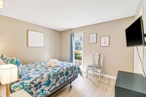 A bedroom with a bed, a chair, a desk, and a window.