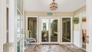 Hotellin sisäänkäynti, jossa on kivilaatoitettu lattia, suuri kattokruunu ja kyltti, jossa lukee: ”Beach House”.