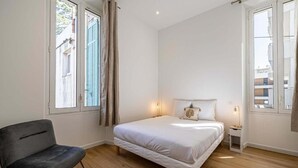Ein Schlafzimmer mit einem Bett, einem Sessel und einem Nachttisch.
