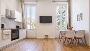 Eine moderne Küche mit Einbauofen, einem kleinen Tisch mit Stühlen und einem an der Wand montierten Fernseher.