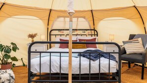 Een tent met een bed, een stoel en een lamp.