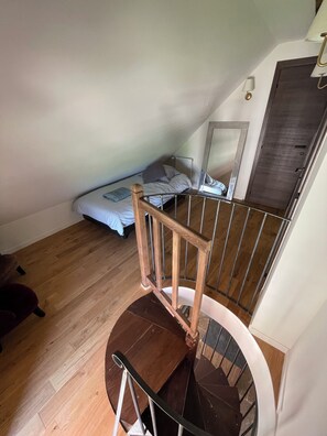 A room with a wooden staircase, a bed with white bedding, and a small table. - Gite du vigneron, Château de Meauce (Saincaize-Meauce)